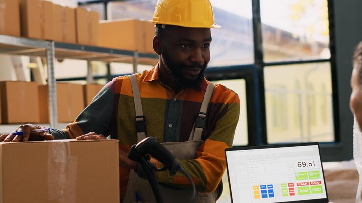 Warehouse worker with a handheld scanner beside a laptop